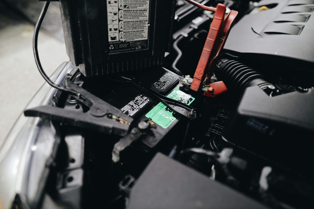 Close-up of a car battery being inspected and maintained, showing clean terminals and a mechanic checking connections for a long-lasting battery life